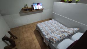 Habitación con sofá y TV en la pared. en Pousada Encosta da Fé en Juazeiro do Norte