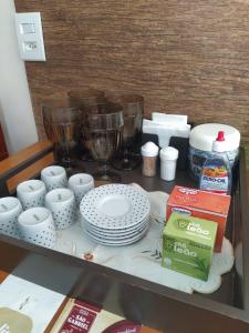 a table with plates and cups and bowls on a counter at Flat Capitolio Charlene Paiva in Capitólio +11 photos