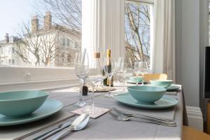 uma mesa com pratos e copos de vinho e uma janela em Newly decorated central 2-bed 2-bath flat em Brighton & Hove
