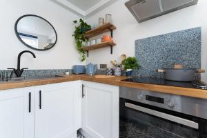 uma cozinha com armários brancos, um lavatório e um espelho em Bright and Beautiful studio apt with king size bed em Brighton & Hove