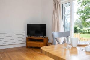 a living room with a television on a wooden table at Countryside Cottage with Stunning Views in Fletching