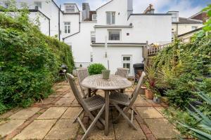 - une table et des chaises sur une terrasse avec une maison dans l'établissement Contemporary & Colourful Flat + Garden, à Brighton et Hove