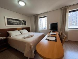 a hotel room with a bed and a desk with a television at Suíte 5 estrelas Hotel Moema Times Square 1412 in Sao Paulo