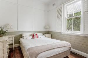 een witte slaapkamer met een bed en een raam bij Meroo Meadow Magic - Charming Cottage Retreat in Meroo