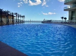 a large pool of blue water with palm trees at Book Santos - Unlimited 1112 - Um Pé na areia in Santos