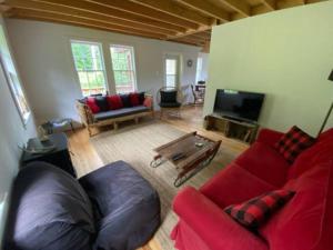 ein Wohnzimmer mit einem Sofa und einem TV in der Unterkunft Le Highwater - Cabin in Mansonville