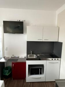 a small kitchen with white cabinets and a sink at Ariston Hotel in Sindelfingen