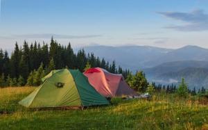 twee tenten op een grasheuvel met bergen op de achtergrond bij Tapian Asri Camp in Bukittinggi