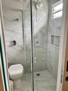 uma casa de banho com um WC e uma cabina de duche em vidro. em Hotel Lorimar em Penha