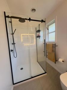 a bathroom with a shower with a glass door at Village Cottage in Havelock North