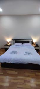 a bedroom with a large white bed with two lamps at Hotel Max Comfort in Kutaisi