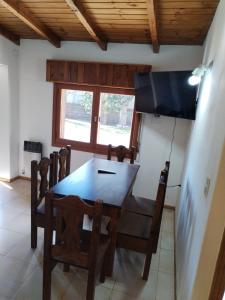 a dining room with a table and chairs and a television at Cómodo Hogar con Jardín in San Carlos de Bariloche
