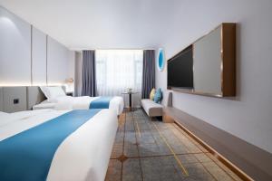 um quarto de hotel com duas camas e uma televisão de ecrã plano em Poltton International Hotel - Huizhou University of economics em Huizhou