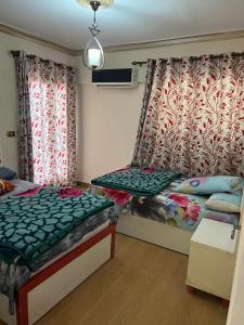 um quarto com 2 camas e uma janela com cortinas em Tyvally Dom apartment sea view للعائلات فقط em Alexandria