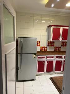 uma cozinha com um frigorífico branco e armários vermelhos em Tyvally Dom apartment sea view للعائلات فقط em Alexandria