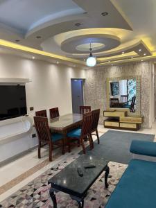 uma sala de estar com uma mesa e cadeiras e uma televisão em Tyvally Dom apartment sea view للعائلات فقط em Alexandria