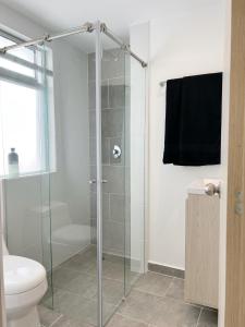 La salle de bains est pourvue d'une douche en verre et de toilettes. dans l'établissement LUNA NUEVA *Céntrico & Cama Queen, à Sabaneta