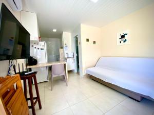 a bedroom with a white bed and a kitchen at Casinha da Praia in Aracaju