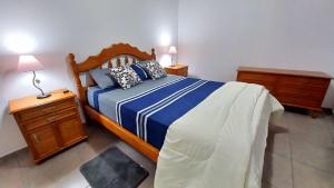 a bedroom with a bed with a blue and white comforter at Sueños Del Pilar II # Mendoza # Casa Depto en G Cruz # Estacionamiento # Bodegas in Mendoza