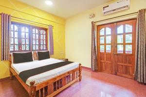 een slaapkamer met een bed en een houten deur bij Ferns Guest House in Calangute