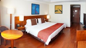 a hotel room with a large bed and a table at HOTEL ILAR ESPERANZA CERCA DE EMBAJADA EEUU Y CORFERIAS in Bogotá