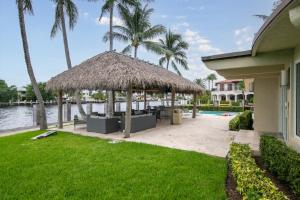 a patio with a straw umbrella and a swimming pool at Paradise Manor in Pompano Beach