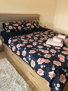 a bed with a black and pink floral comforter at Apartment TAJM in Trebinje