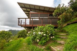 a house on the side of a hill with flowers at Owl's Watch Nature Retreat in Manizales