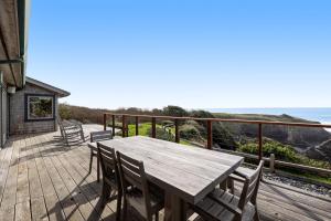 - une table et des chaises en bois sur une terrasse donnant sur l'océan dans l'établissement Perched on the Bluff - Main Home & Studio Cottage, à Mendocino