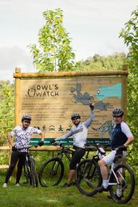un grupo de tres personas en bicicleta delante de un cartel en Owl's Watch Nature Retreat en Manizales