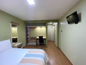 a bedroom with a bed and a desk with a television at Huallata Hotel Boutique in Huaraz