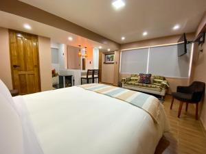 a bedroom with a large bed and a living room at Huallata Hotel Boutique in Huaraz