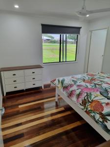 a bedroom with a bed and a dresser and a window at Yungaburra Whitehouse in Yungaburra