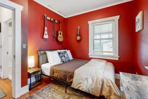 ポートランドにあるBeaumont Bungalowの赤い壁とギターが壁に掛けられたベッドのある寝室