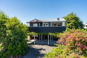 a house on the beach with bushes and flowers at Close to the Lake in Taupo