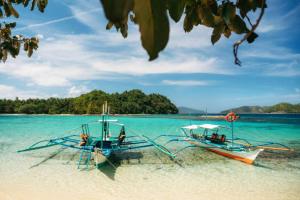 two boats sitting on a beach in the water at Trisha Guesthouse in San Vicente