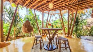 a table and stools in a room with trees at The Bamboo Houses - Tropical Garden & Empty Beach in General Luna