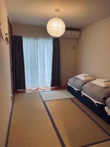 ゲストハウス and BAR CHITEN في Awaji: غرفة بسريرين ونافذة كبيرة