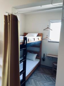 a room with two bunk beds and a desk at ゲストハウス and BAR CHITEN in Awaji