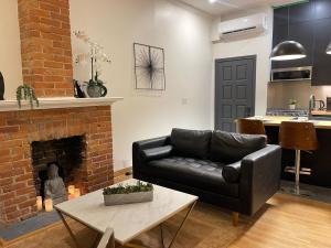 een woonkamer met een leren bank en een open haard bij 3 Bedroom Victorian with Deck and Parking in Toronto