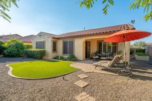 une maison avec un parasol et une pelouse dans l'établissement The Chandler Villa, à Chandler