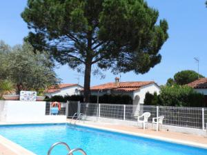 einen Pool mit zwei Stühlen und einem Baum in der Unterkunft Apartamento L'Escala, 2 dormitorios, 4 personas - ES-325-37 in Torroella de Montgrí