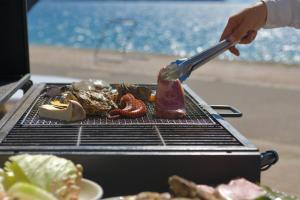 een persoon is vlees aan het grillen op een grill bij Uminos Spa & Resort in Etajima