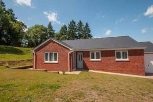 a red brick house with a grass yard at Stylish Bungalow in Symonds Yat in Hereford