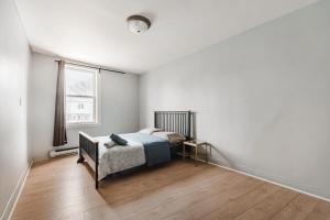 a white bedroom with a bed and a window at Spacious 3 bedroom apartment in Lasalle - 72 in Montreal