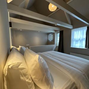 een slaapkamer met een groot bed met witte kussens bij Hotel Grand Canal in Delft