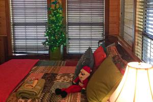 um urso de peluche sentado numa cama com uma árvore de Natal em Rudolph - Reindeer Ranch at Round Top em Carmine