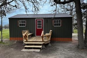 un cobertizo verde con terraza y puerta roja en 4 Cabins - Reindeer Ranch at Round Top, en Carmine