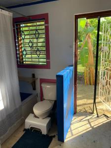 a bathroom with a toilet and a window at Humble Boy retreat Glamping yurt in Negril