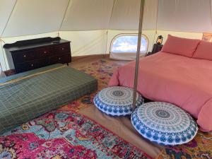 a bedroom with a bed and two rugs in a tent at Humble Boy retreat Glamping yurt in Negril